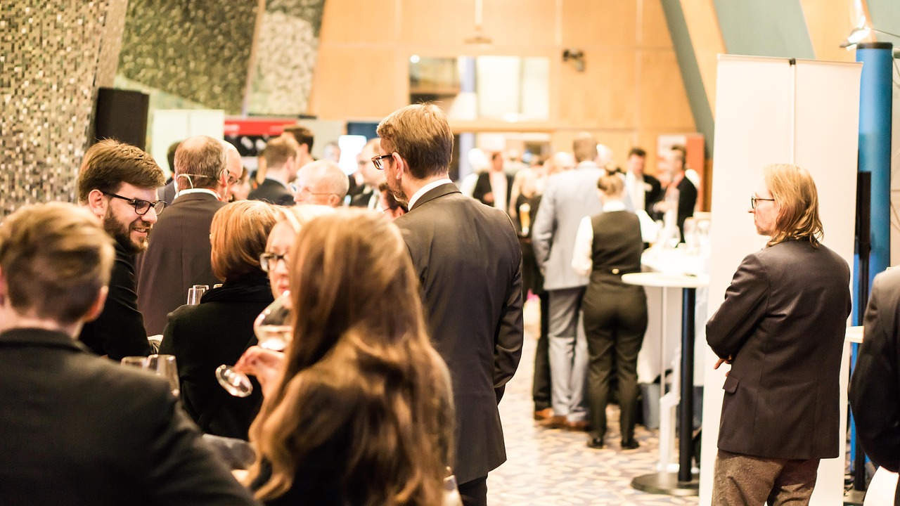 Professionals networking at a business event, engaged in conversation in a conference setting.